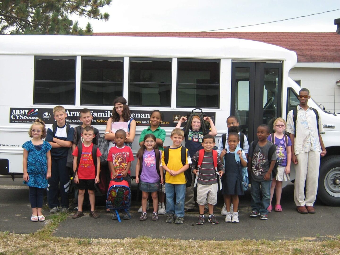A bunch of kids standing near a bus and packed and ready to go