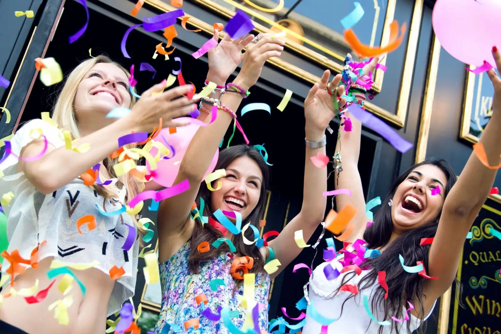 A bunch of girls playing with confetti and balloons